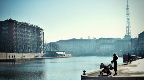 Man on river by city against clear sky