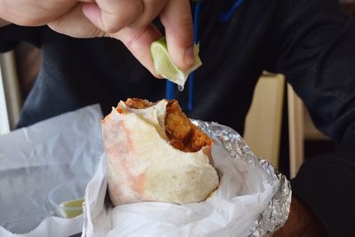 Close-up of a hand squeezing lime on sandwich