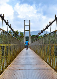 Rear view of boy walking on footbridge