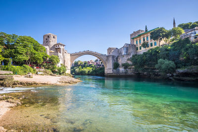 Arch bridge over river against blue sky