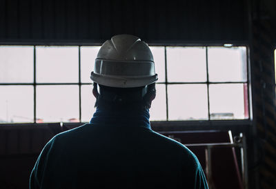 Rear view of man standing against window