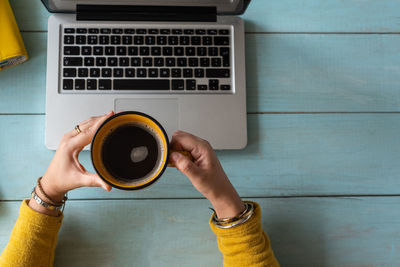Directly above shot of hand holding coffee cup on table