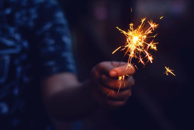 Midsection of person holding illuminated sparkler