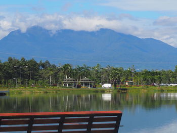 Scenic view of lake by trees and mountains against sky