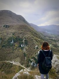 Rear view of man standing on mountain against sky