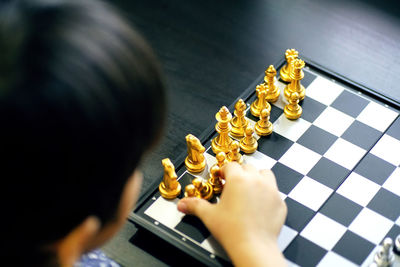 High angle view of hand holding chess piece onboard