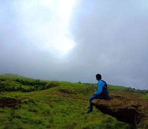 Rear view of man standing on mountain against sky