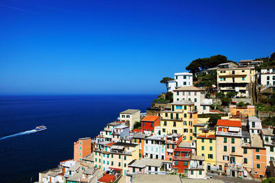 High angle view of residential buildings by sea against blue sky