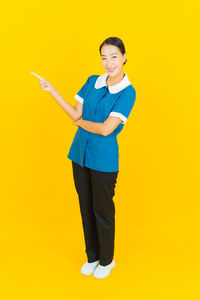 Portrait of smiling young woman against yellow background