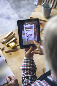 Midsection of man using mobile phone on table
