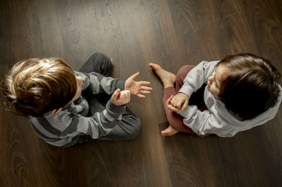 Boy with brother playing rock paper scissors on floor at home