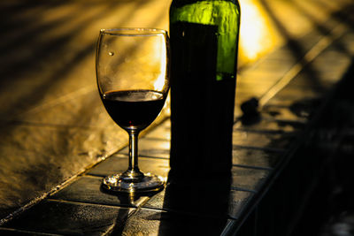 Close-up of wine in glass and wine bottles by the pool and the last light .