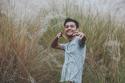Portrait of smiling teenage boy standing amidst grass