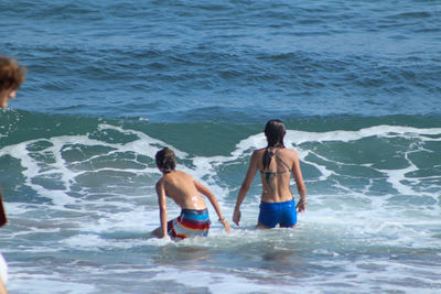 Rear view of shirtless men in sea