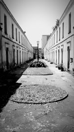 Narrow street along canal and buildings against clear sky