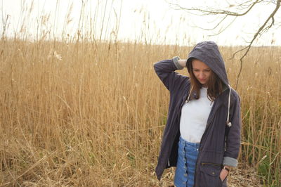Woman wearing hooded shirt and standing in field