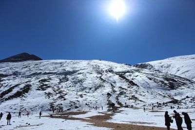 Scenic view of snow covered mountains against clear blue sky