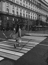 Rear view of woman walking on road in city