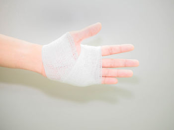 Cropped hand with bandage against white background