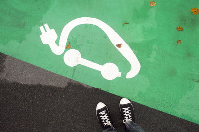 Low section of person standing on road sign