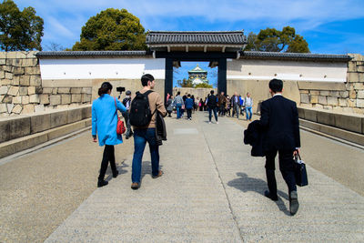 Rear view of people walking in front of building