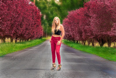 Full length portrait of woman with pink umbrella on road