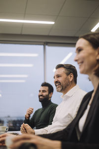 Happy business colleagues working late while discussing in meeting at work place