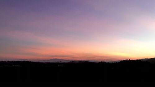 Silhouette landscape against dramatic sky during sunset