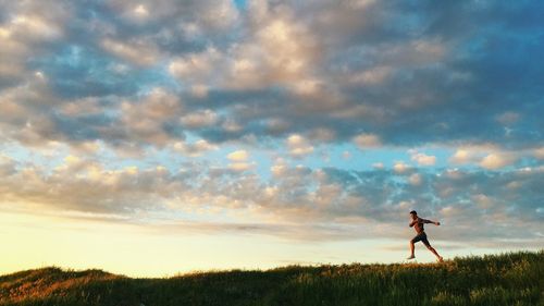 Silhouette man running on field against sky during sunset