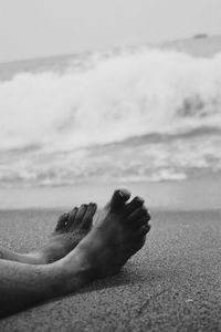 Close-up of person relaxing on beach against sky