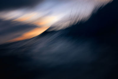 Defocused image of sea against sky at sunset