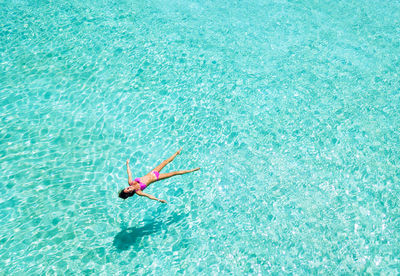 High angle view of woman swimming in sea on sunny day