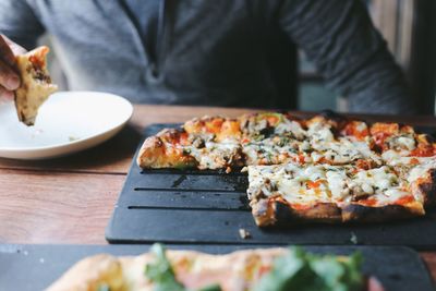 Midsection of man having pizza in restaurant