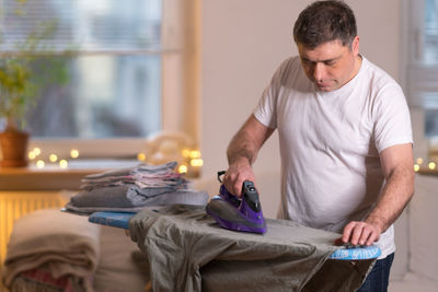 Man ironing clothes at home