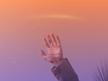 Close-up of person hand against sky during sunset