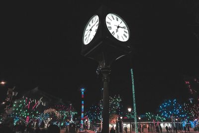 Low angle view of illuminated clock tower at night