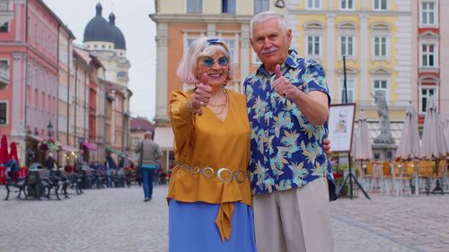 Senior tourist couple showing thumbs up while standing in town