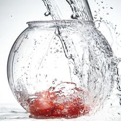 Close-up of water splashing on glass against white background