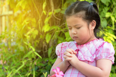 Close-up of girl praying against plants
