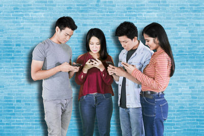 Young couple holding hands while standing on mobile phone