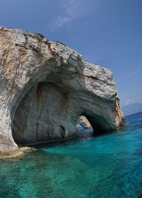 Rock formation in sea against blue sky