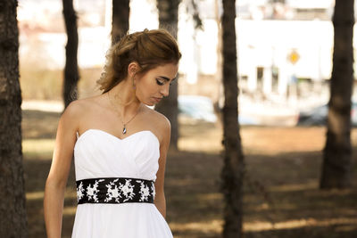 Young woman looking away while standing outdoors