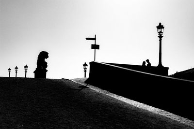 Silhouette people on street against clear sky