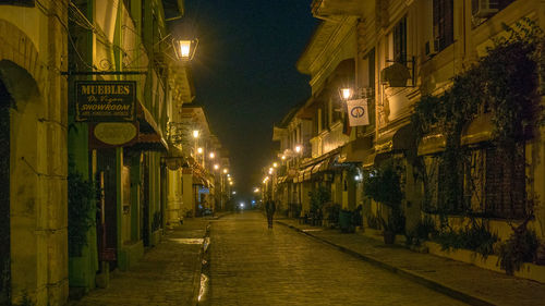 Illuminated street amidst buildings at night