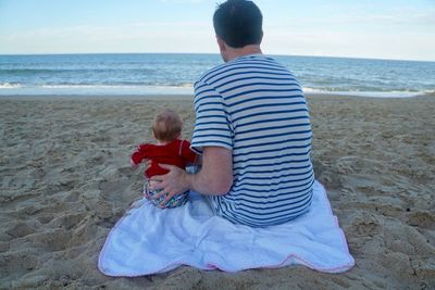 Rear view of friends on beach against sky