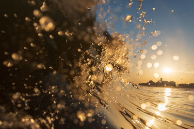 Water drops on illuminated sea against sky during sunrise