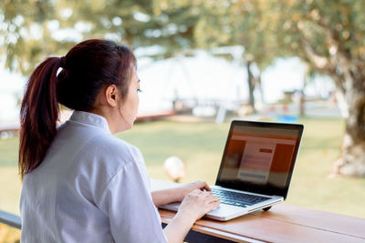 Side view of woman using mobile phone at table