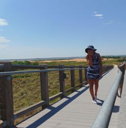 Full length of man standing on railing against sky