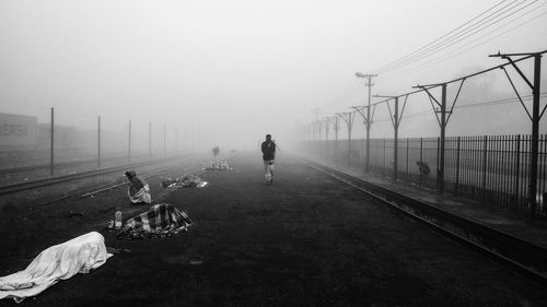 People on empty footpath during foggy weather