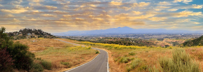 Scenic view of road amidst field against sky